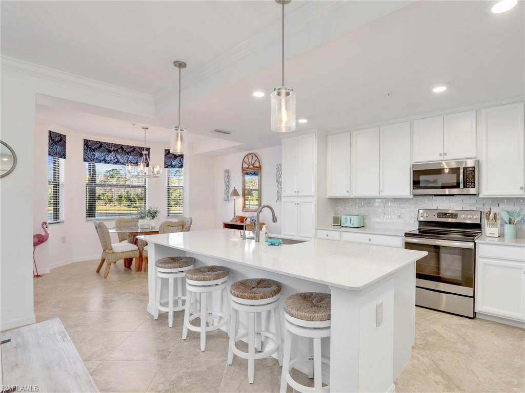 9584 Trevi Court, Unit 5213 Naples, FL 34113 - Photo 6 of 50 a kitchen with stainless steel appliances granite countertop a stove a sink a center island a dining table and chairs