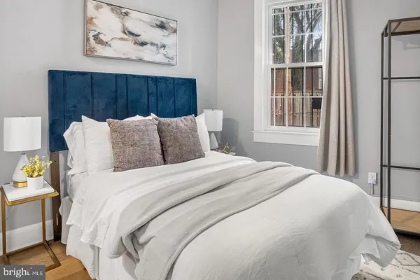 a bedroom with a bed a painting on the wall and a window