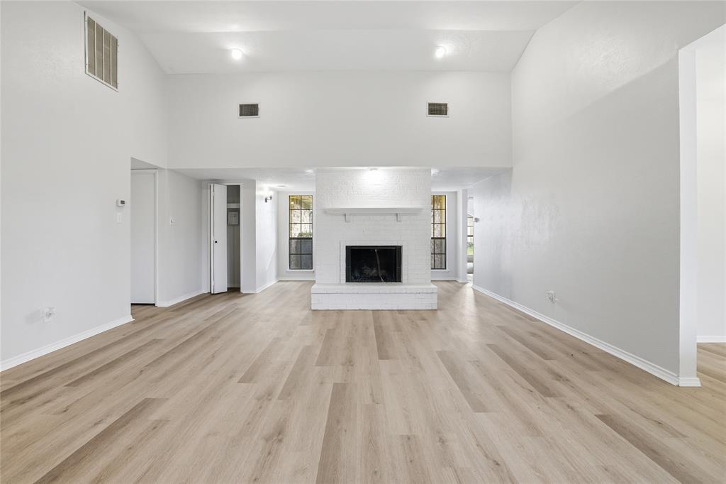 403 Redbud Drive Forney, TX 75126 - Photo 4 of 17 an empty room with wooden floor and a kitchen