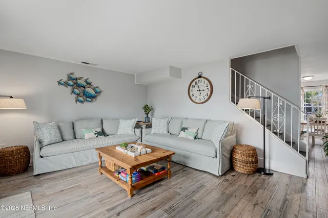a living room with furniture a rug potted plant and a large window