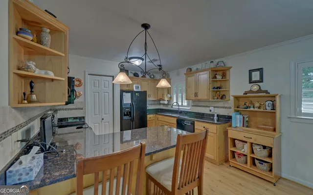a dining hall with stainless steel appliances granite countertop a kitchen island a stove a refrigerator a oven a dining table and chairs with wooden floor