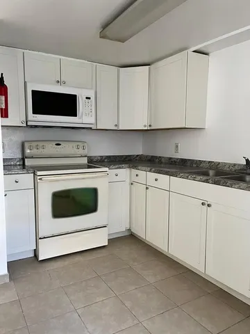 a white kitchen with granite countertop white cabinets and stainless steel appliances