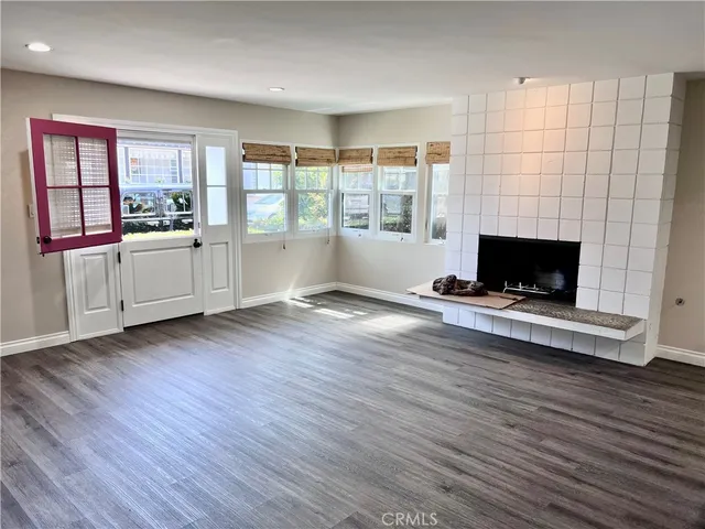 an empty room with wooden floor fireplace and windows