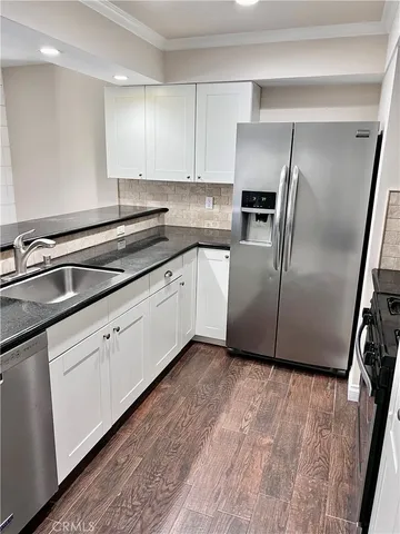 a kitchen with granite countertop a refrigerator sink and cabinets
