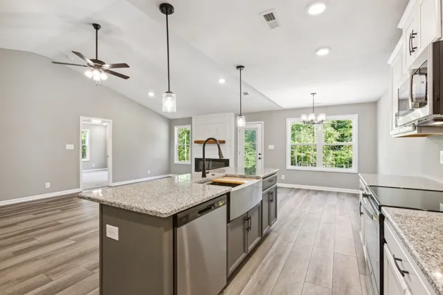 a kitchen with stainless steel appliances granite countertop a sink a stove a refrigerator cabinets and wooden floor