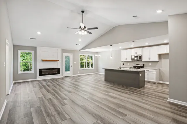 an empty room with wooden floor fireplace and windows