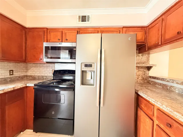 a kitchen with stainless steel appliances granite countertop a refrigerator a stove a sink and dishwasher with wooden cabinet