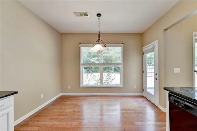 a view of an empty room with window and wooden floor