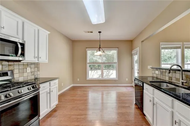 a kitchen with stainless steel appliances a sink a stove a microwave and wooden floor