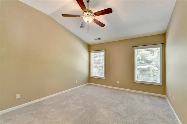 an empty room with windows and fan