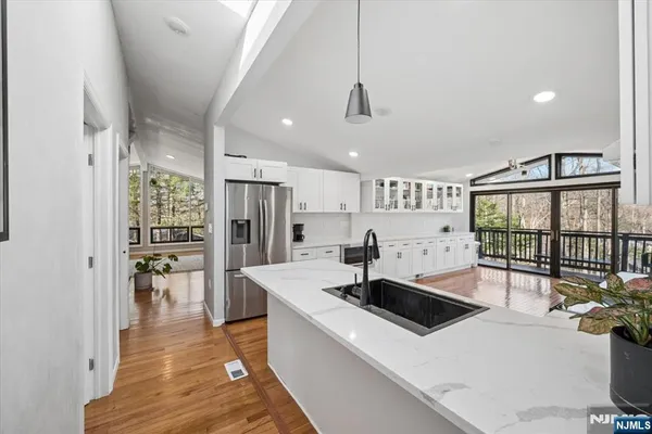 a kitchen with granite countertop a stove a sink a refrigerator and white cabinets with wooden floor