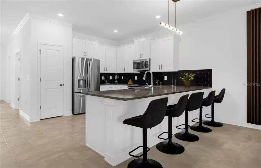 2992 Penelope Loop Kissimmee, FL 34746 - Photo 12 of 83 a kitchen with stainless steel appliances kitchen island granite countertop a refrigerator a stove a sink counter tops and chairs with wooden floor