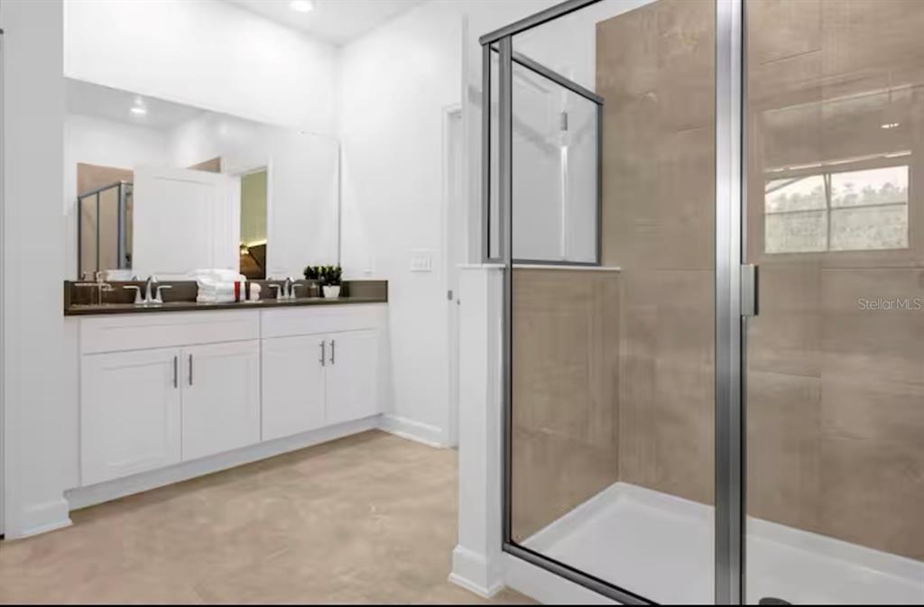 2992 Penelope Loop Kissimmee, FL 34746 - Photo 54 of 83 a bathroom with a double vanity sink a mirror and shower