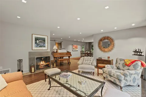 a living room with furniture two large window and wooden floor