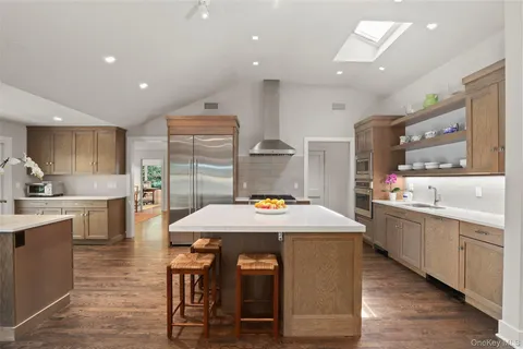 a kitchen with stainless steel appliances kitchen island granite countertop a table chairs sink and cabinets