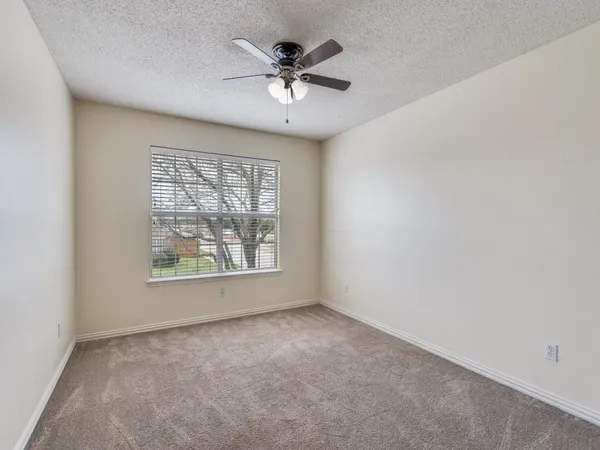 an empty room with a window and a ceiling fan