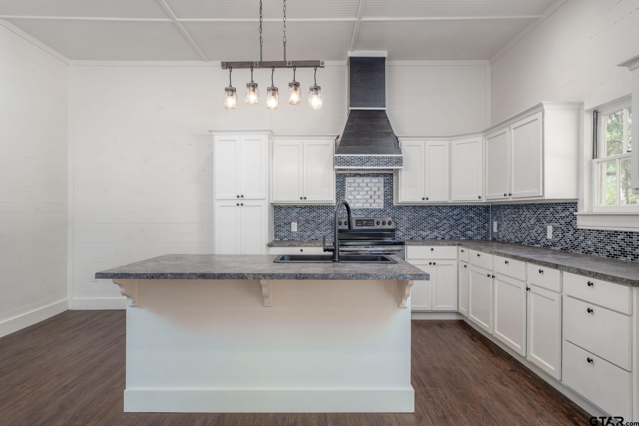 605 East Calvert Street Troup, TX 75789 - Photo 13 of 23 a kitchen with kitchen island granite countertop a sink a stove and cabinets
