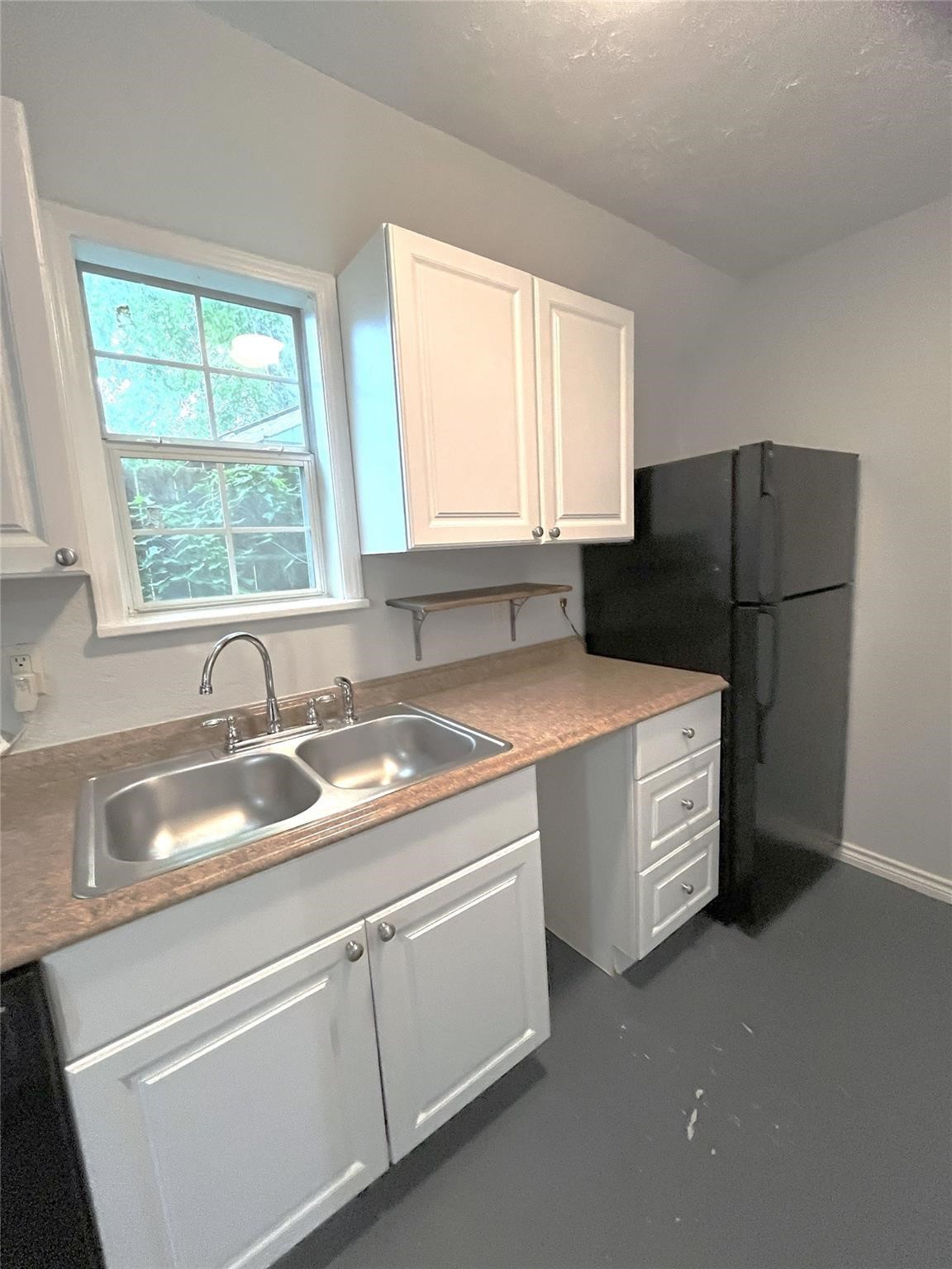 1127 Walling Street, Unit 2 Houston, TX 77009 - Photo 6 of 15 Charming kitchen with bright natural light, featuring sleek white cabinetry, a double sink, and a spacious black refrigerator.