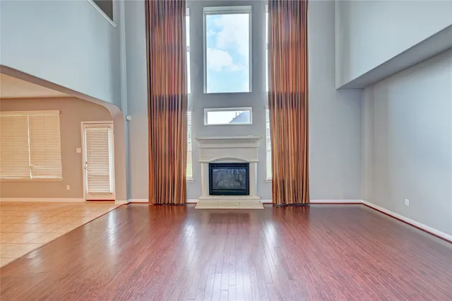 an empty room with wooden floor fireplace and windows