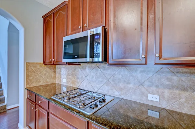 a kitchen with granite countertop a sink cabinets and stainless steel appliances