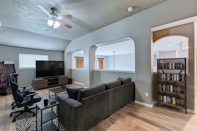 a view of an empty room with wooden floor and a ceiling fan