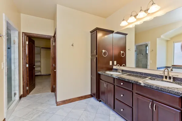 a spacious bathroom with a granite countertop sink a mirror and a shower