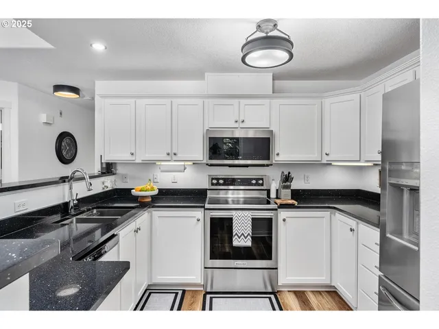 a kitchen with granite countertop a stove a sink and a microwave