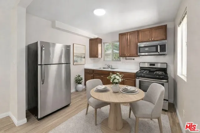 a kitchen with stainless steel appliances a refrigerator a stove a sink a dining table and chairs