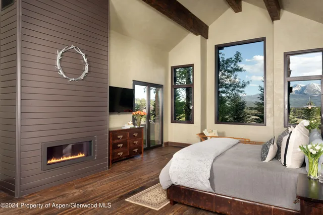 a bedroom with a bed a flat screen tv and a fireplace