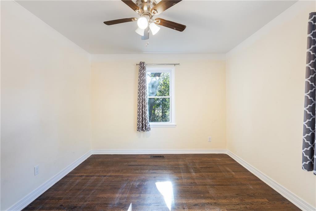 5287 Maple Valley Road Southwest Mableton, GA 30126 - Photo 12 of 29 an empty room with wooden floor chandelier fan and windows
