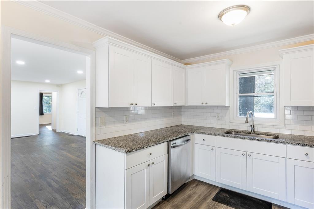 5287 Maple Valley Road Southwest Mableton, GA 30126 - Photo 6 of 29 a kitchen with a sink dishwasher and white cabinets with wooden floor