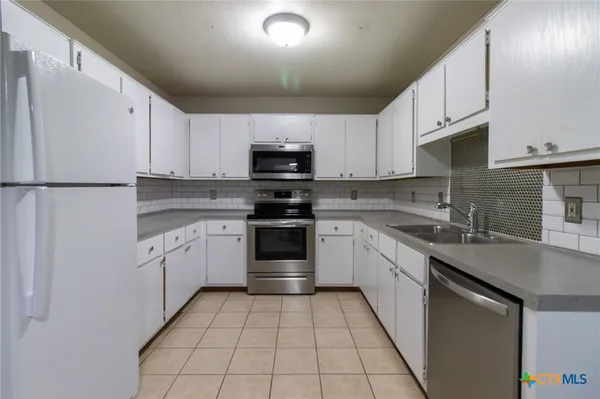 a kitchen with stainless steel appliances granite countertop a refrigerator sink and stove
