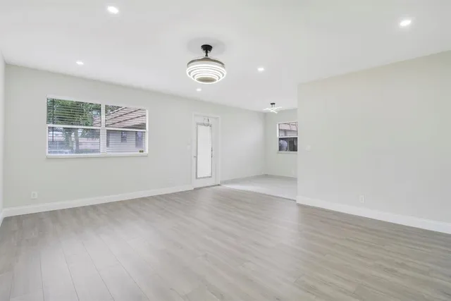 an empty room with wooden floor and windows