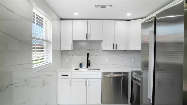 a kitchen with stainless steel appliances white cabinets and a refrigerator