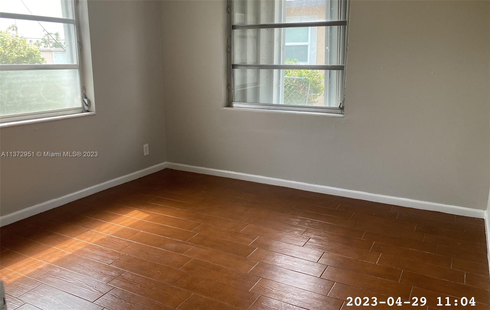 106 Engle Road Lake Worth, FL 33461 - Photo 8 of 10 an empty room with wooden floor and windows