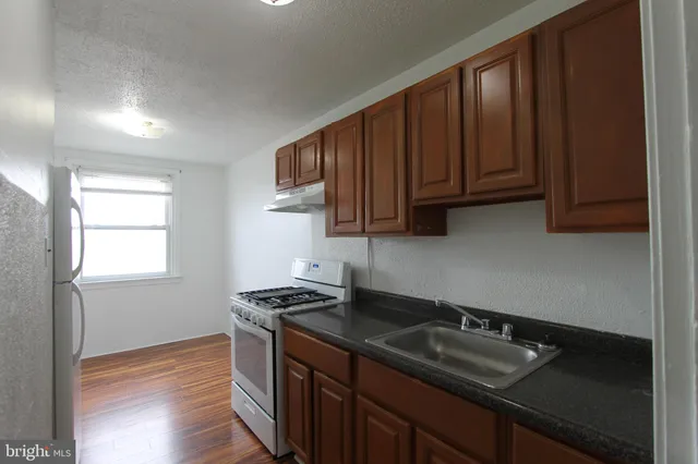 a kitchen with granite countertop a sink stove and cabinets