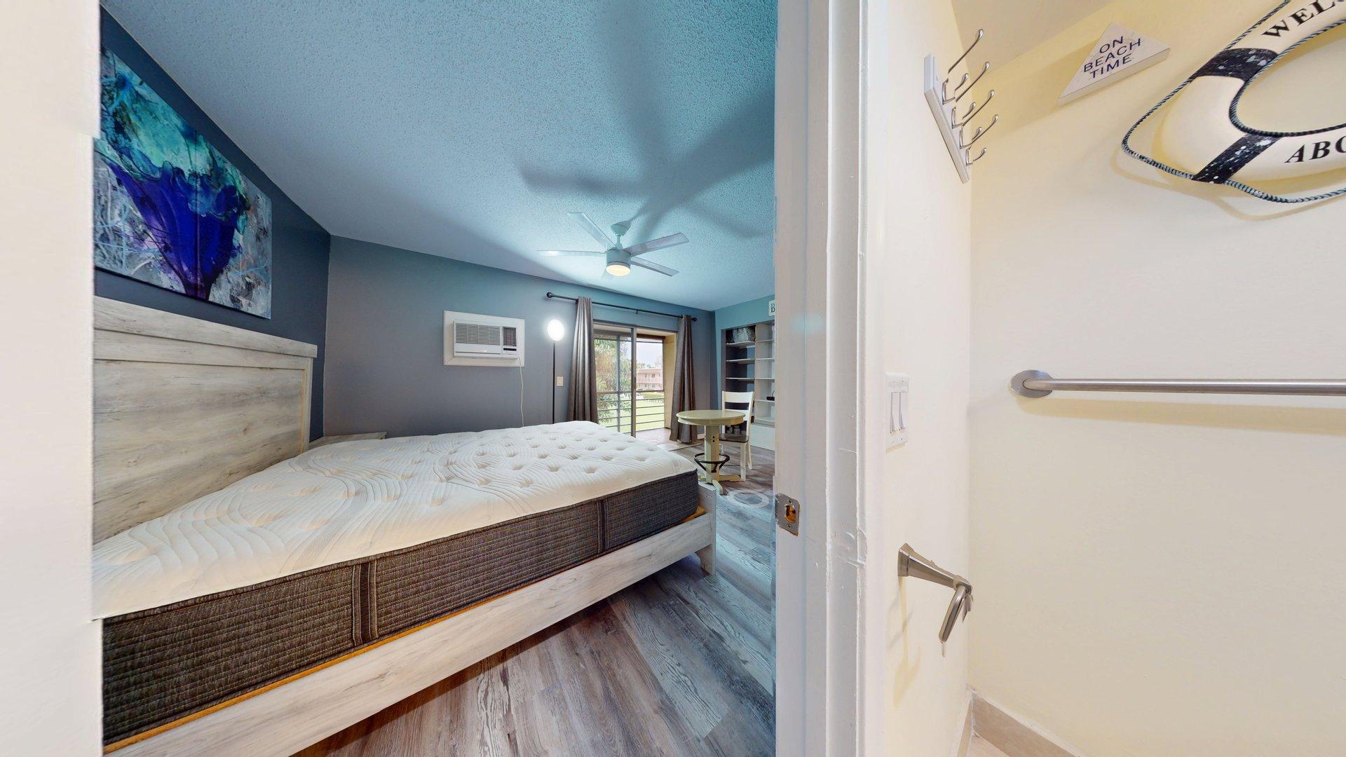 130 Dorchester East, Unit F West Palm Beach, FL 33417 - Photo 14 of 28 a bedroom with a large bed and a painting on the wall