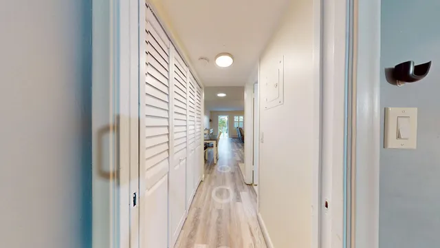 a view of a hallway with wooden floor and a bathroom