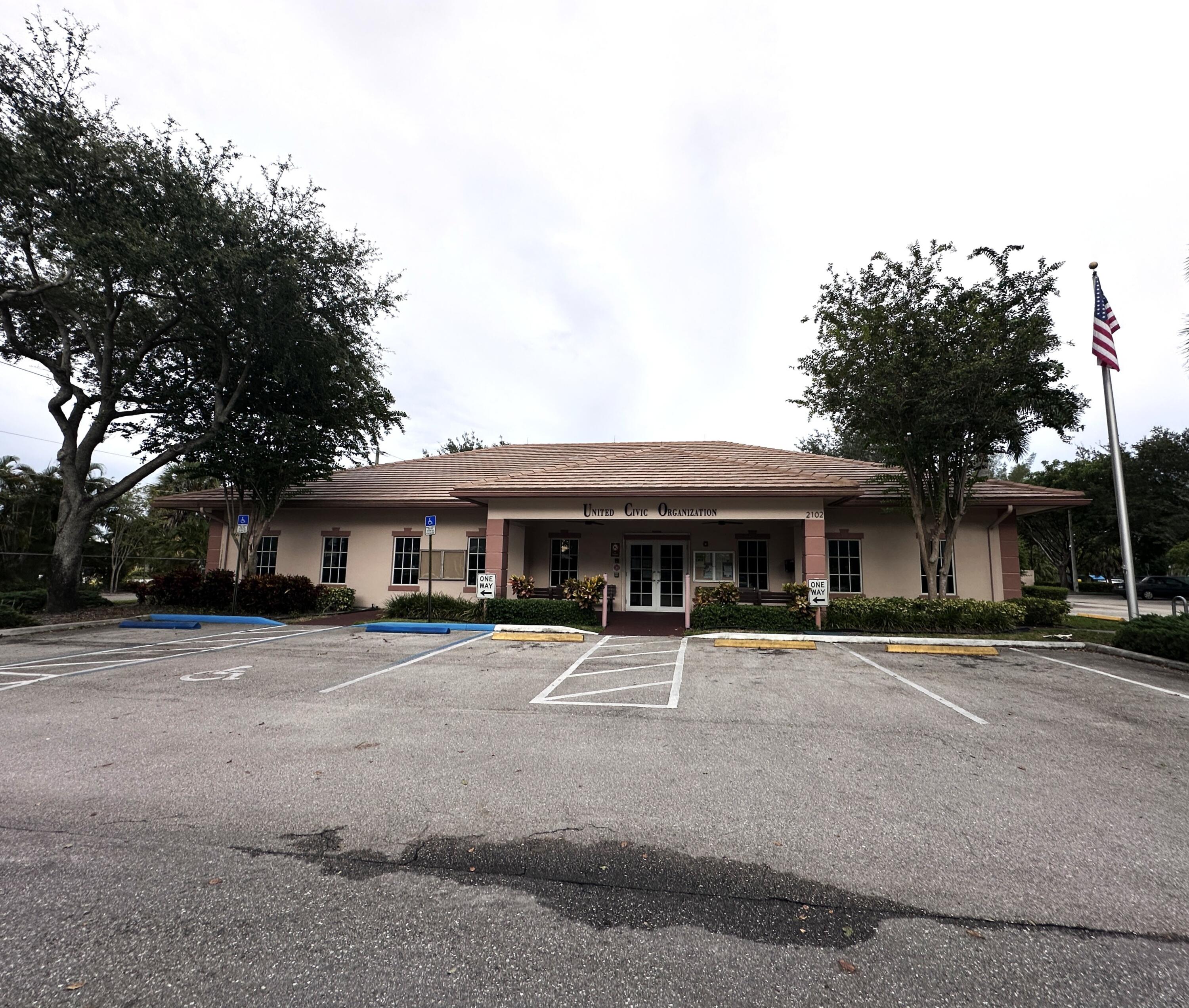 130 Dorchester East, Unit F West Palm Beach, FL 33417 - Photo 26 of 28 a front view of a house with a yard and large trees