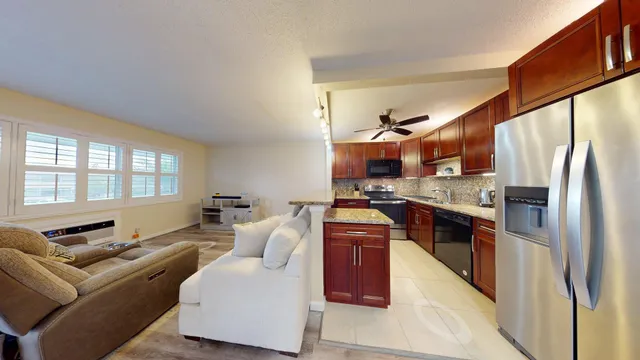 a living room with stainless steel appliances granite countertop furniture a couch and a large window