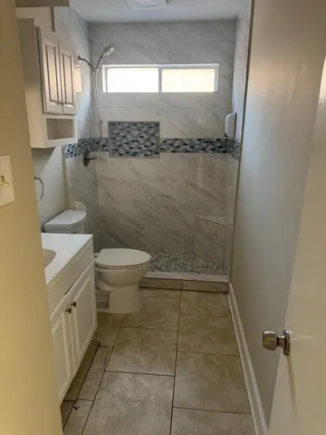 a bathroom with a granite countertop sink a toilet and a shower