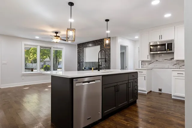 a kitchen with kitchen island granite countertop a sink cabinets and wooden floor