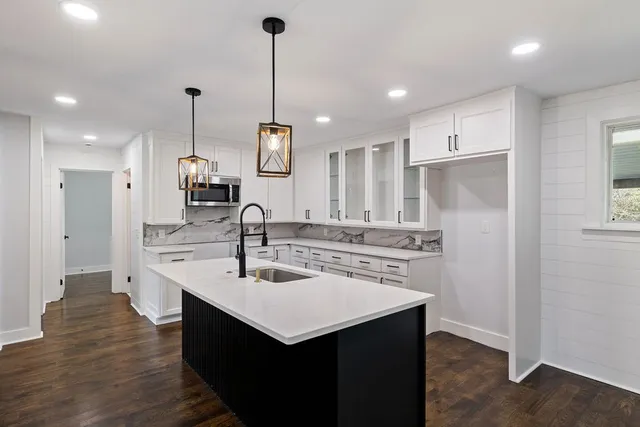 a kitchen with a sink a center island stainless steel appliances and cabinets