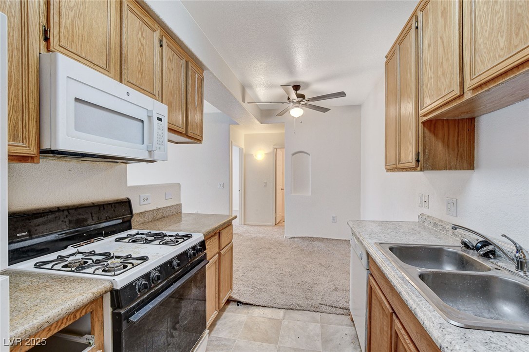 3318 North Decatur Boulevard, Unit 1061 Las Vegas, NV 89130 - Photo 16 of 49 Kitchen featuring white appliances, light countertops, a ceiling fan, and light carpet
