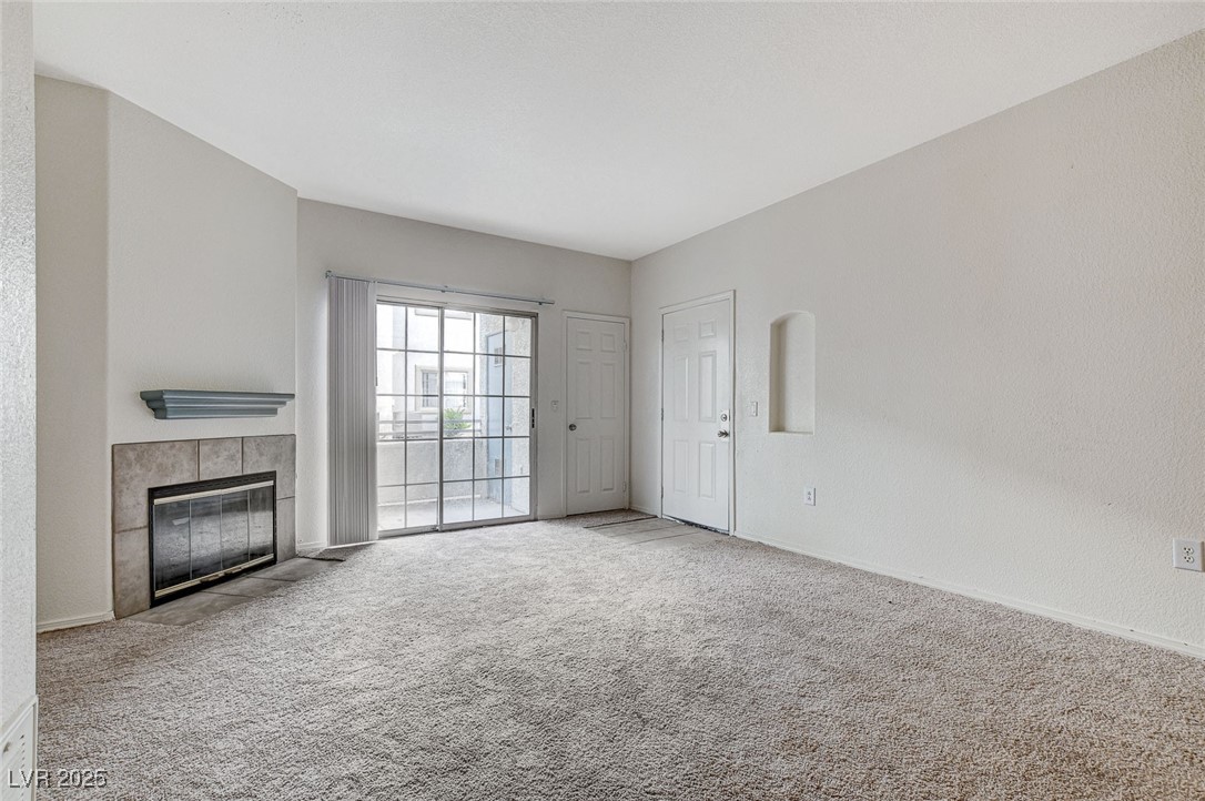 3318 North Decatur Boulevard, Unit 1061 Las Vegas, NV 89130 - Photo 8 of 49 Unfurnished living room featuring carpet floors and a fireplace