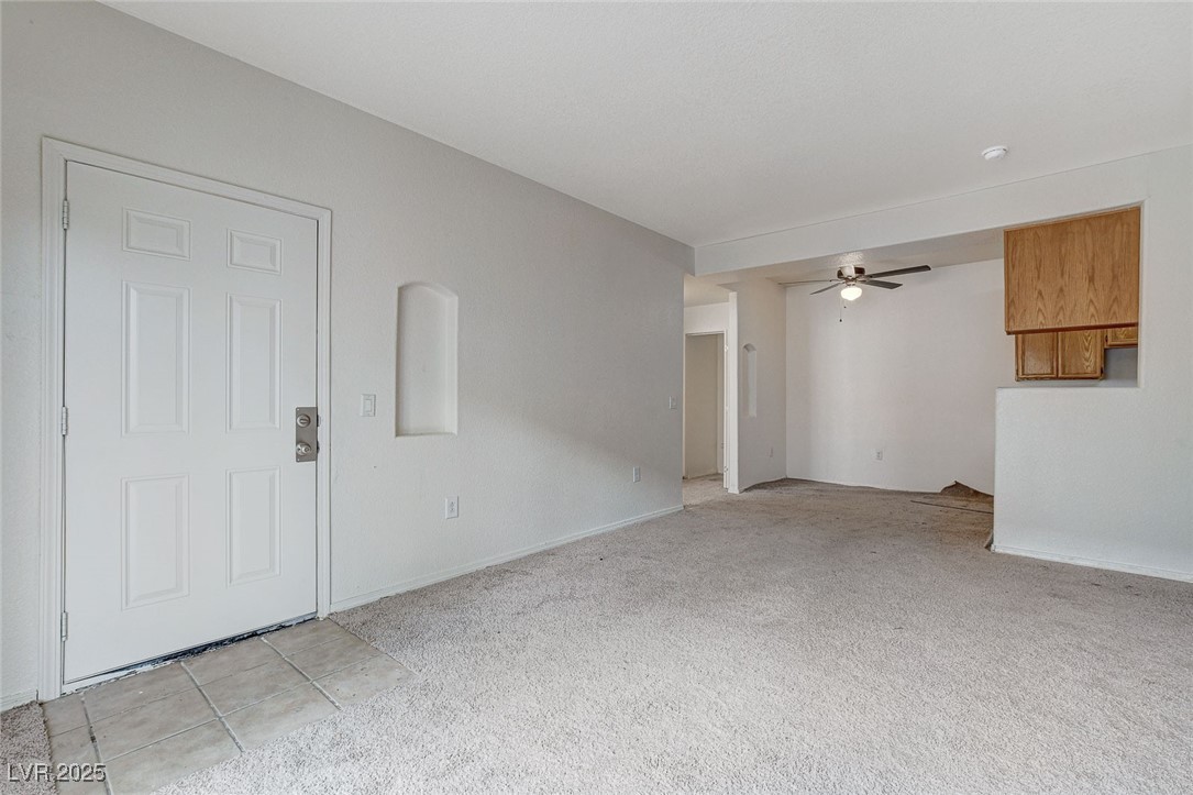 3318 North Decatur Boulevard, Unit 1061 Las Vegas, NV 89130 - Photo 9 of 49 Unfurnished living room featuring light carpet, ceiling fan, and light tile patterned floors