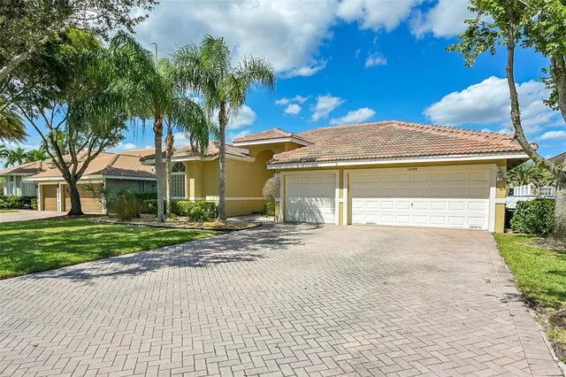 a front view of a house with a yard and palm trees