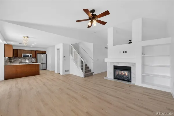 a view of kitchen and empty room with wooden floor fireplace