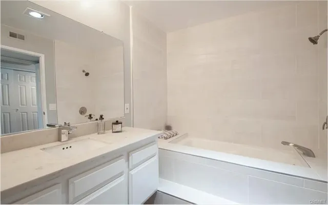 a bathroom with a tub sink and mirror
