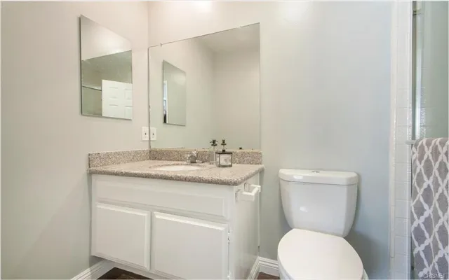 a bathroom with a granite countertop toilet sink and a mirror